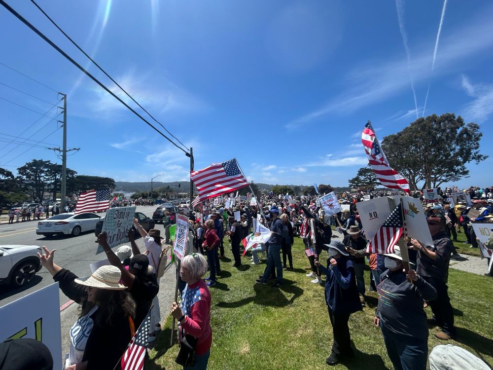 many people signs and flags at the no kings protest in monterey ca