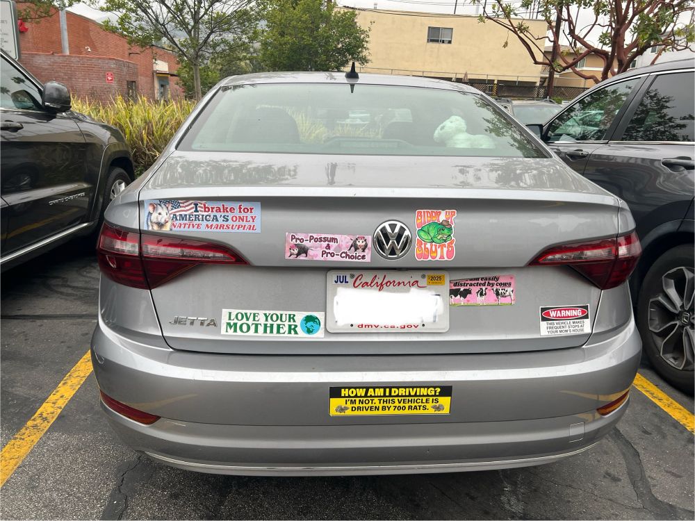 a car laden with various bumper stickers that say things like

"I BRAKE FOR AMERICA'S ONLY NATIVE MARSUPIAL"

"Pro-Possum, Pro-Choice"

"HOW AM I DRIVING? I'M NOT. THIS VEHICLE IS DRIVEN BY 700 RATS."



