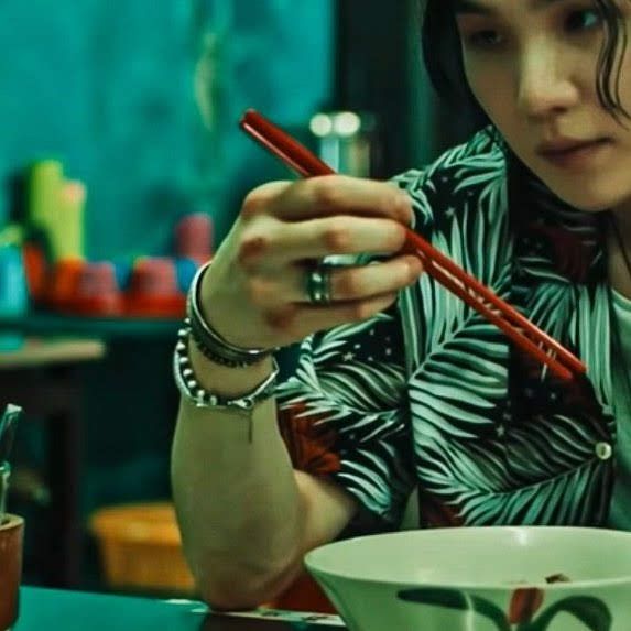 Yoongi holding a pair of red chopsticks from Haegeum music video