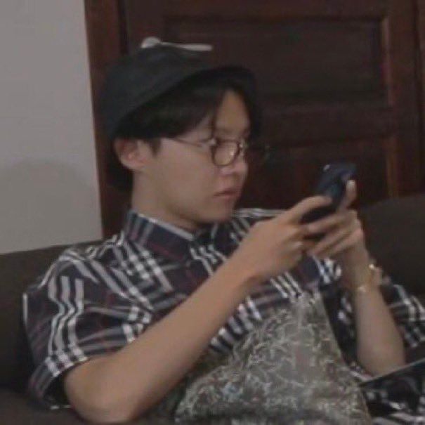 J-Hope holding his phone looking at Jungkook