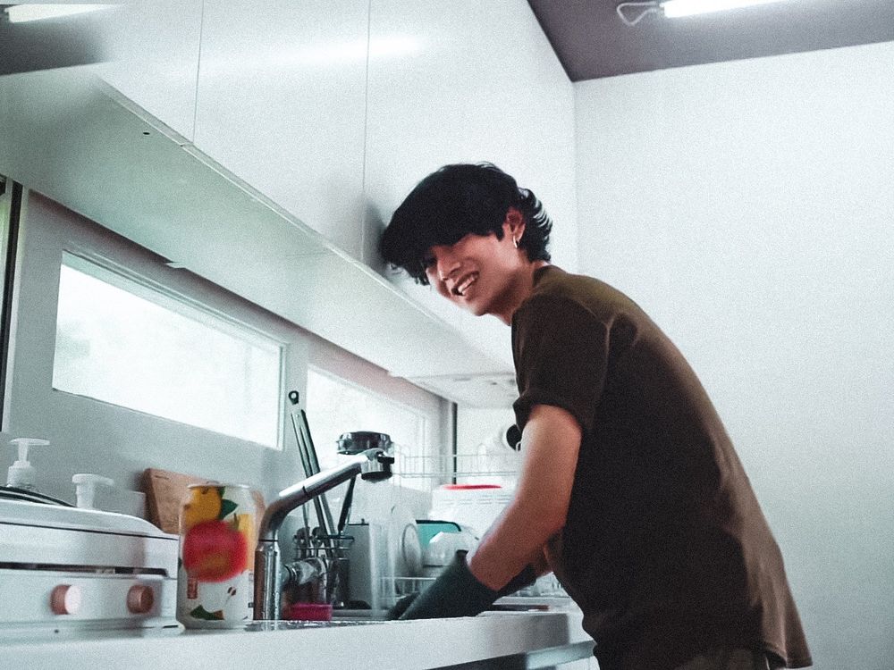 Taehyung standing at a sink washing dishes like the husband that he is.