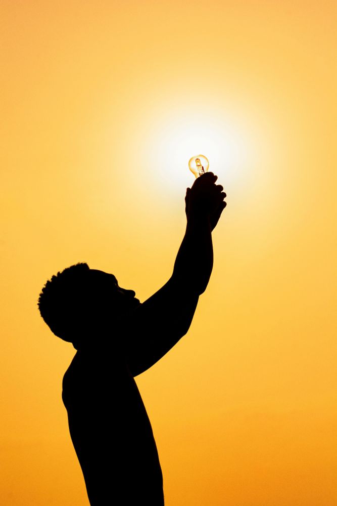 Silhouette of person holding up a light bulb to the sun
Photo by Clement Eastwood via Pexels
