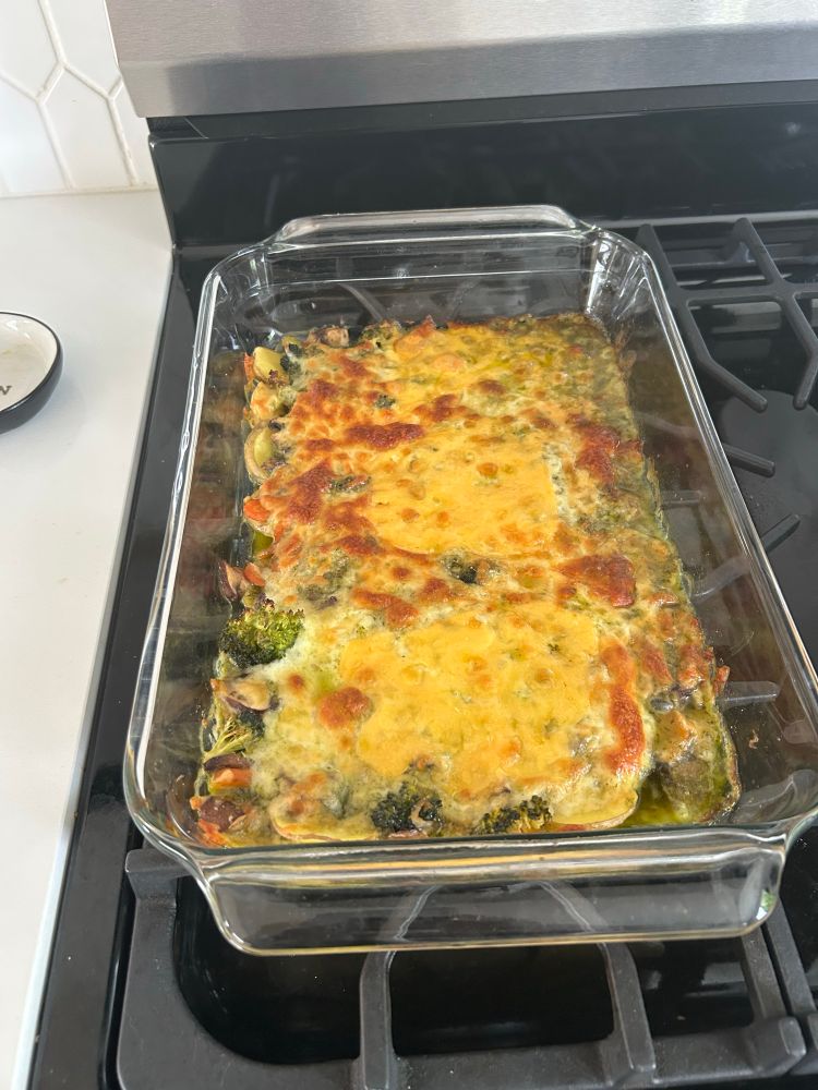 A casserole dish topped with cheese and an assortment of vegetables.
