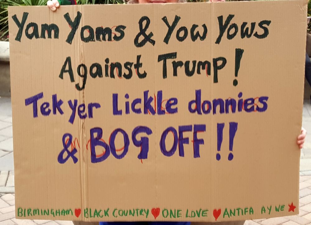 A home made painted cardboard sign reading: Yam yams and yow yows against Trump. Tek yer lickle donnies and BOG OFF!! 
Birmingham (heart) Black Country (heart) One Love (heart) Antifa ay we (star)