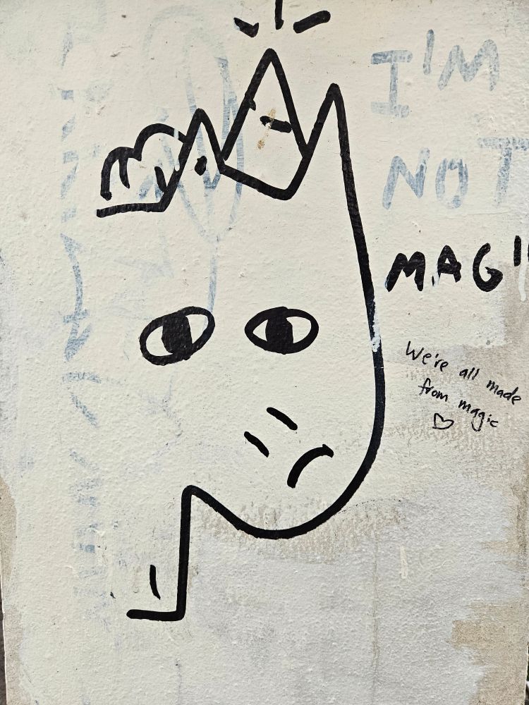 graffitti unicorn saying I'm not magic, someone else has written "We're all made from magic" and drawn a heart. 