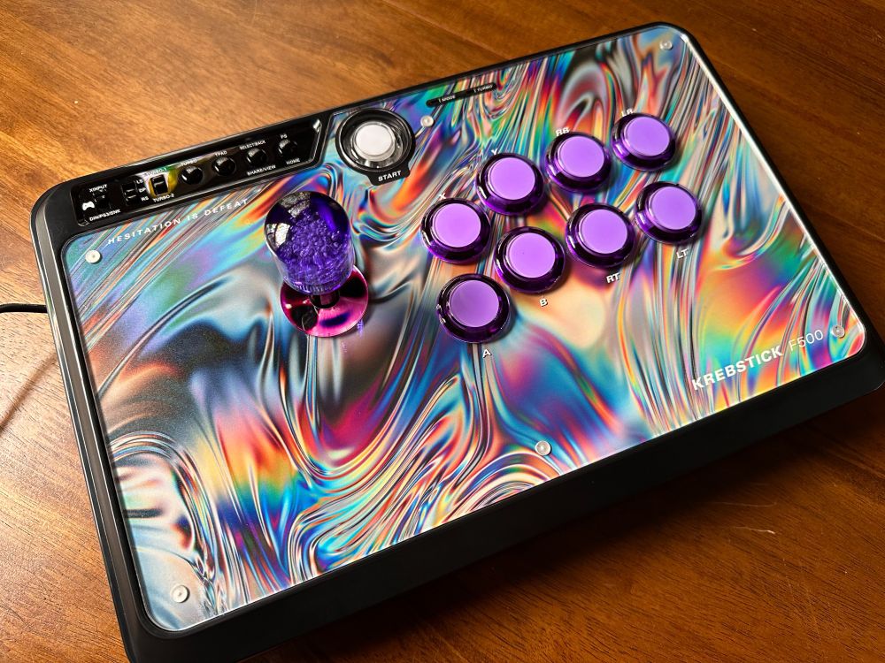 Mayflash F500 V2 arcade stick with custom artwork, featuring a metallic rainbow swirly background, purple buttons, and a translucent purple bullet top handle.
