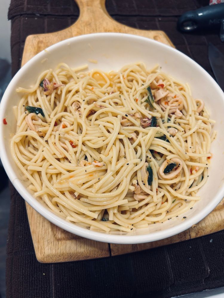 A bowl of lemon Calabrian chile spaghetti with garlic, olive oil, butter, basil, squid, salt and pepper.