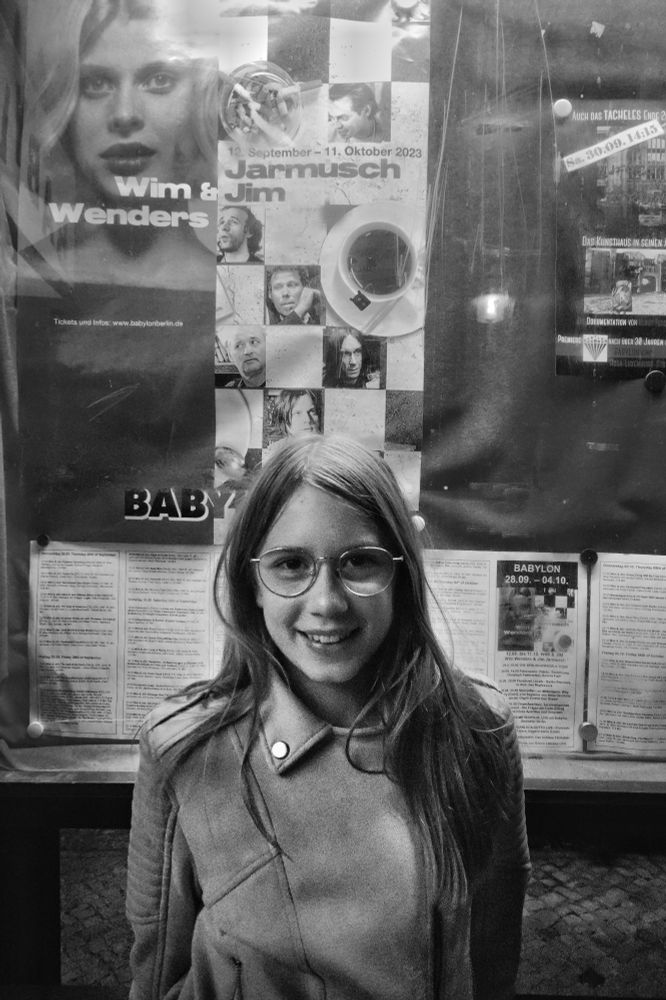 Young girl sitting in front of a movie poster, smiling