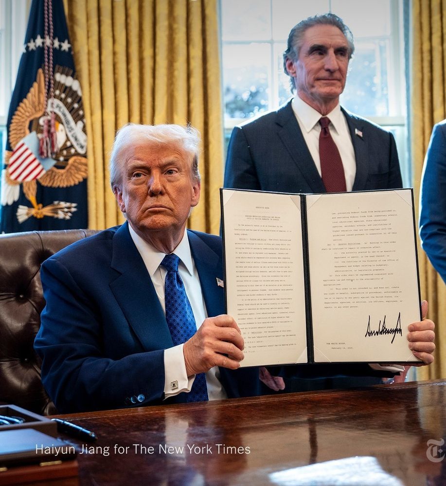 Doug Burgum is situated in the pic to look like he is a pop up page in a pop up book, but the book is an executive order held by Lonny's aid Donald Trump.