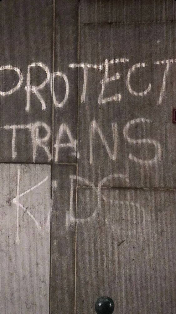 Graffiti auf einer Mauer mit dem Text „Protect trans Kids“
