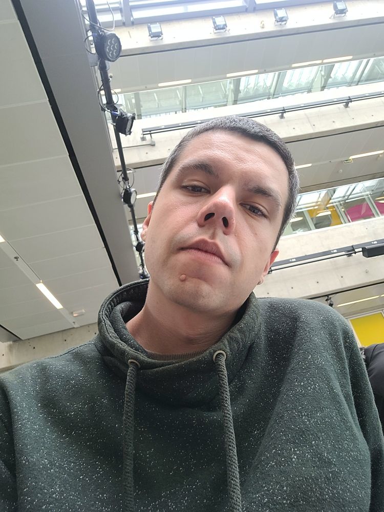 Homem branco com blusa verde olhando para câmera