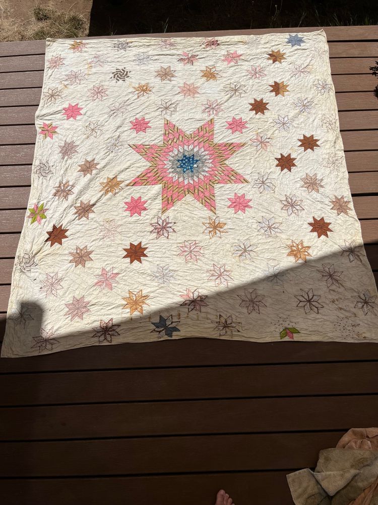 The second quilt, in worse shape (though still reasonably solid for its age). Its design of a larger lone star and many of its surrounding stars are missing large pieces of fabric, and many rusty stains remain. It still looks much brighter and smells much better than before.