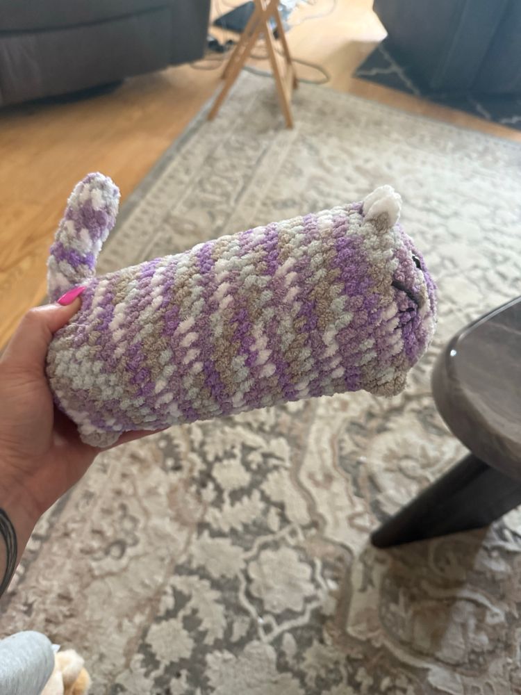 The side view of the purple and grey crocheted cat plushie - he is very long. 
