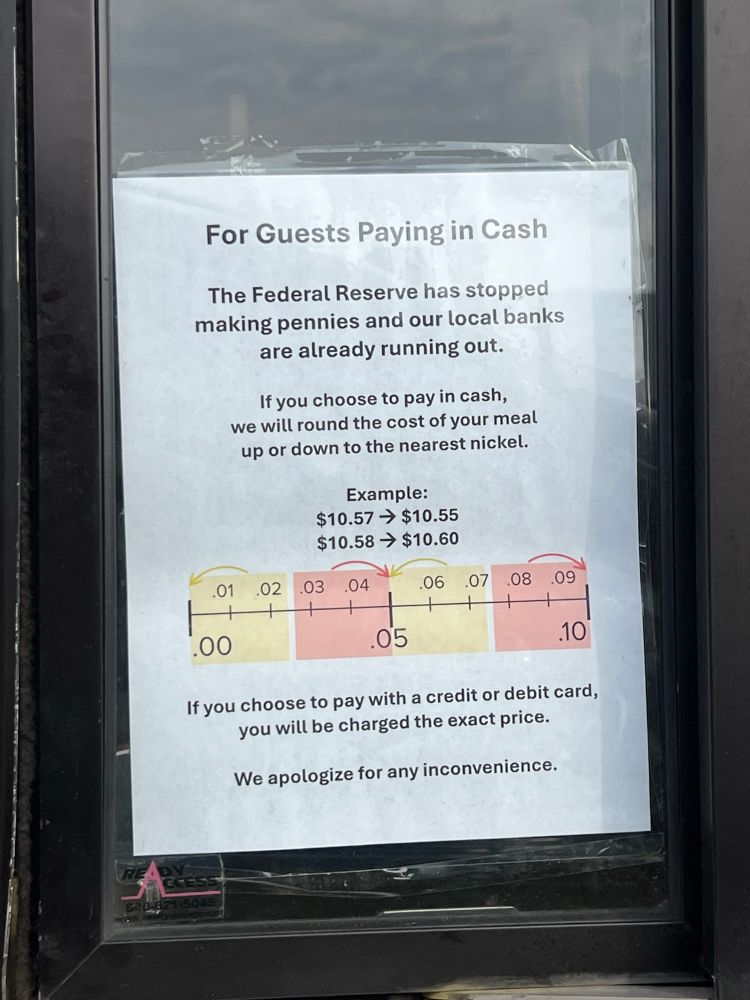 A sign that says: “For guests paying in cash: The Federal Reserve has stopped making Pennie’s and our local banks are already running out. If you choose to pay in cash, we will round the cost of your meal up or down to the nearest nickel.  Example: $10.57–>$10.55; $10.58–> $10.60.  If you choose to pay with a credit or debit card, you will be charged the exact price. We apologize for any inconvenience.”