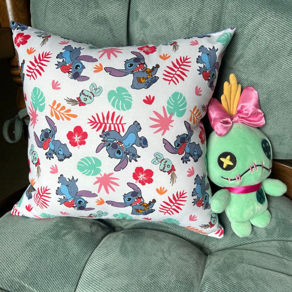 White pillow with Stitch and Scrump on it, sitting on a chair next to a Scrump doll