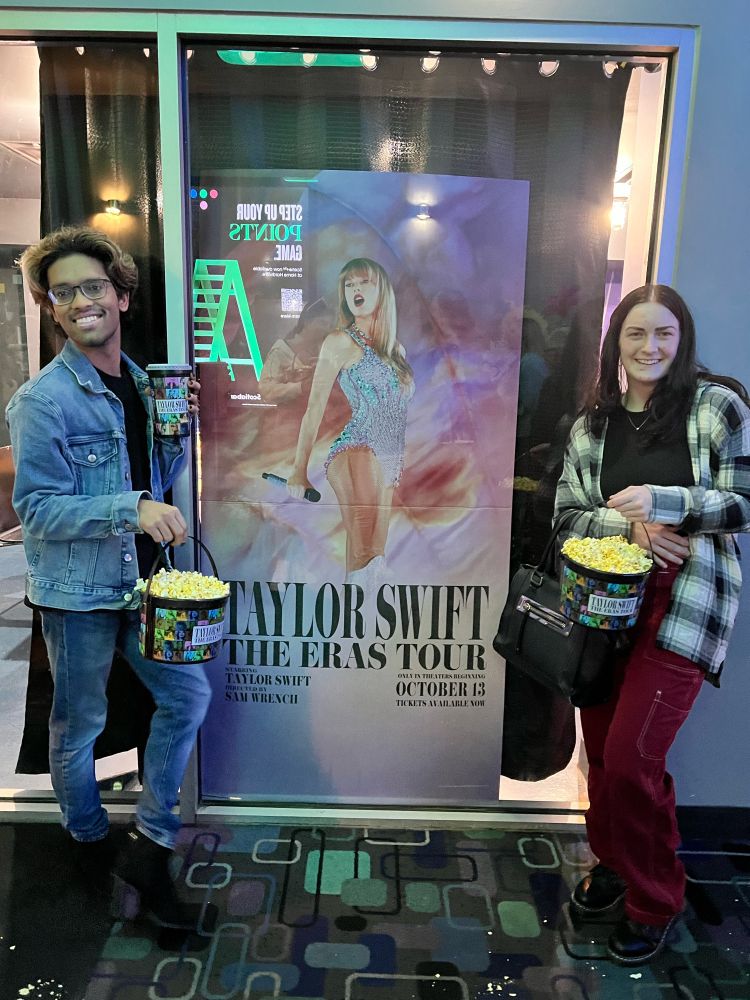 Myself and a friend standing posing with the ERAS movie poster