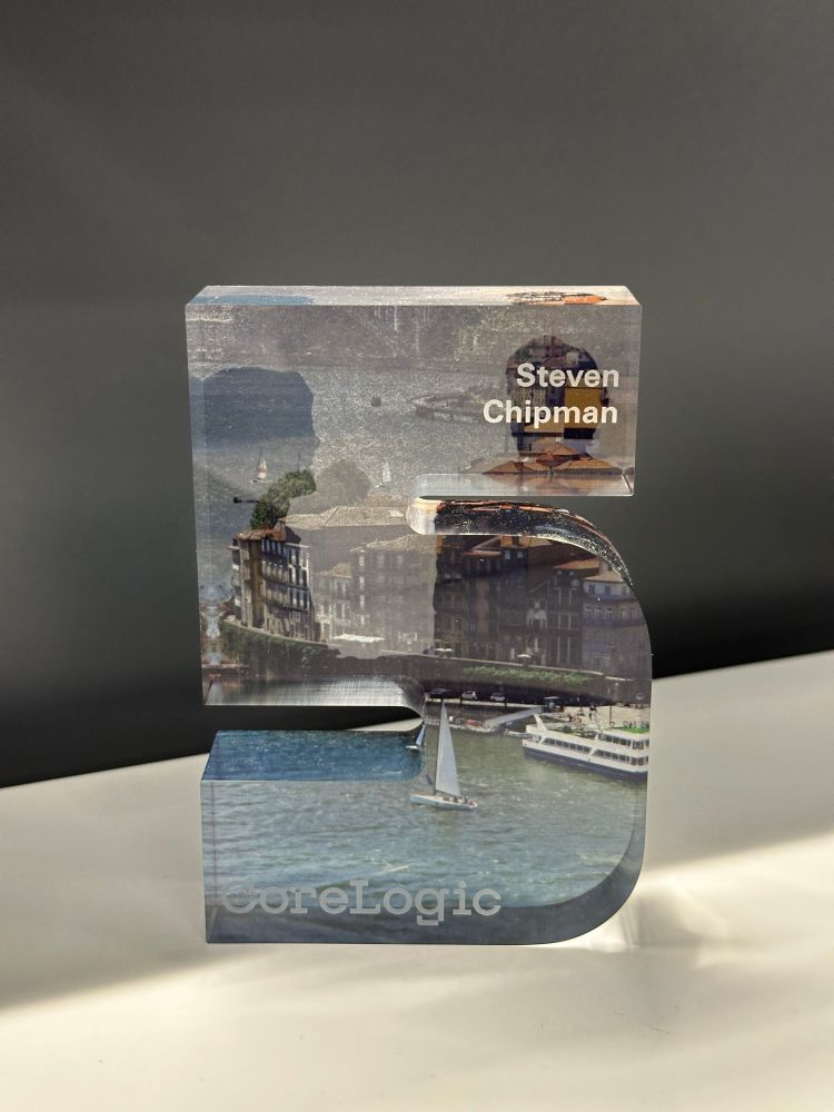 A small, acrylic number five sitting on a desk.