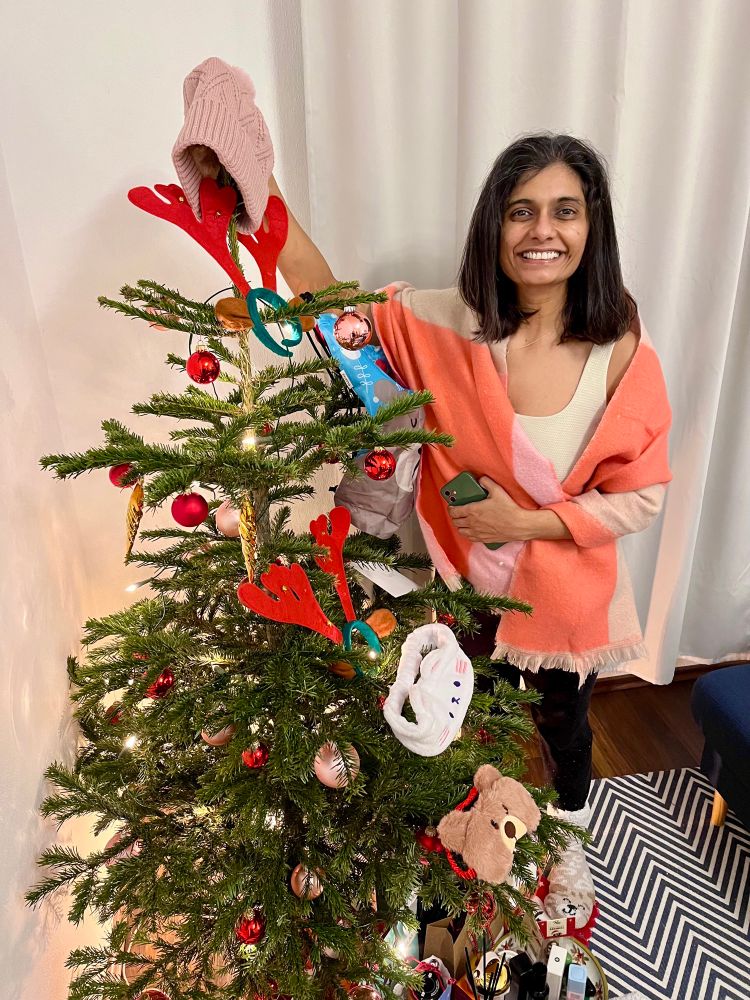 Pranoti with decorated Christmas tree with gifts under it 