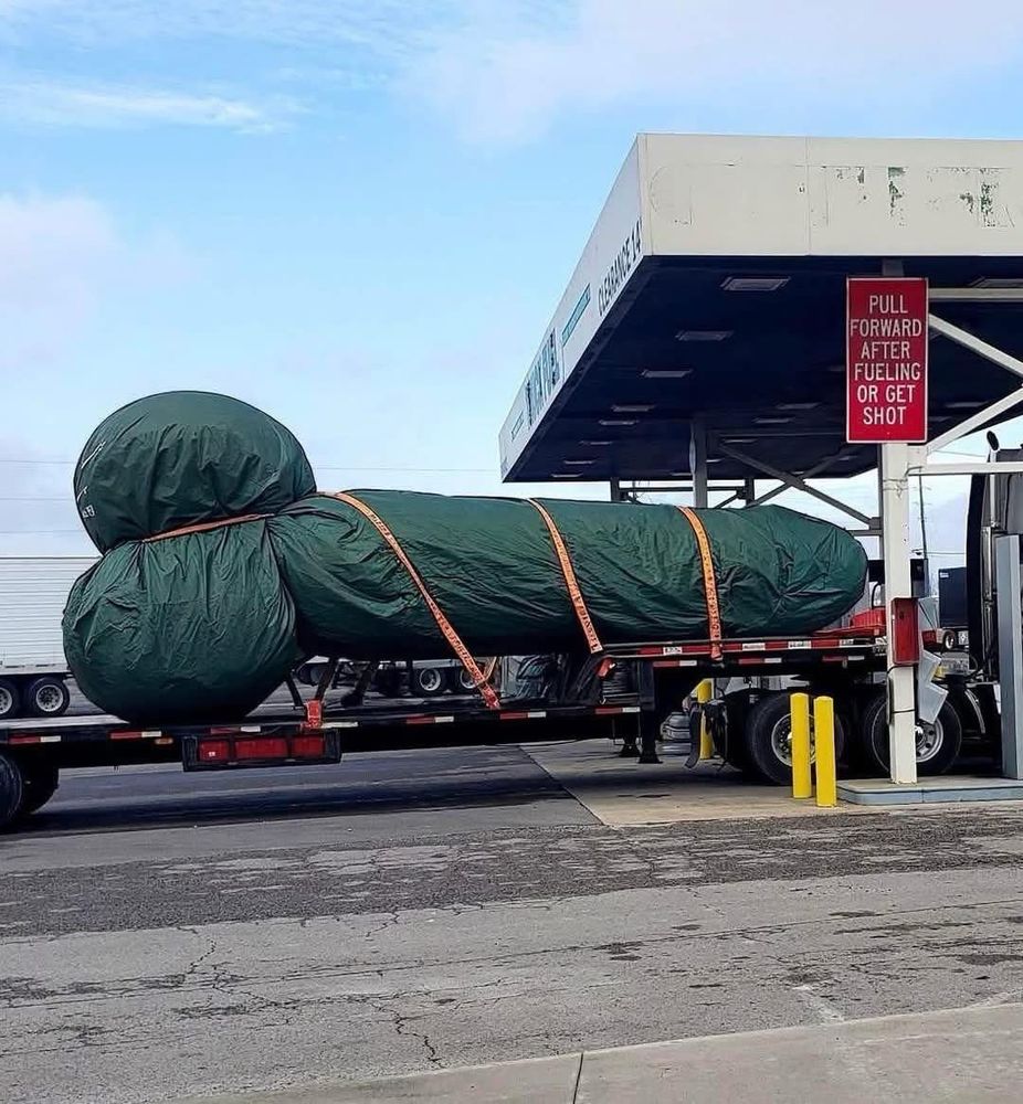 Something wrapped up on the back of semi trailer. Looks like a giant dildo. 
Approximately 4 refrigerators long and 14 rabbits wide. 