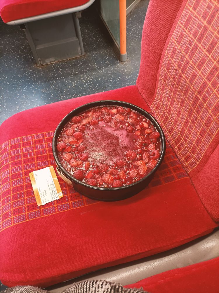 A (delicious looking)
 white chocolate and cranberry cheesecake in its tin on a train seat