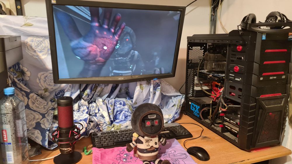 Simon Jarrett, SOMA Protagonist plushie sitting on the makeship bag in front of a pc running SOMA while Simon is looking in a mirror :3