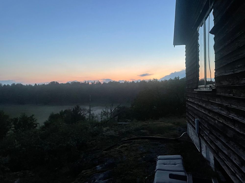 Auch hier, das gleiche Licht, etwas später, Nebel wie kleines Gewölk auf einer Fläche, im Vordergrund eine Hütte in deren Fenster sich der Himmel wiederholt. 