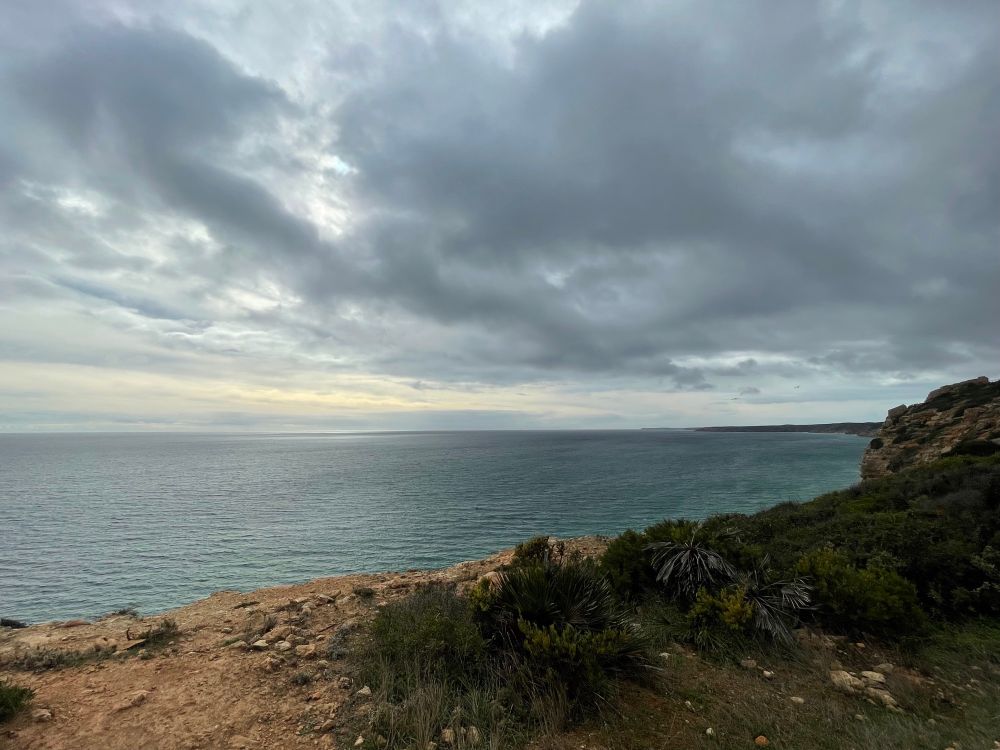 Aufziehender Regen über dem Meer, der Wasserspiegel halb glänzend, halb dunkler.  