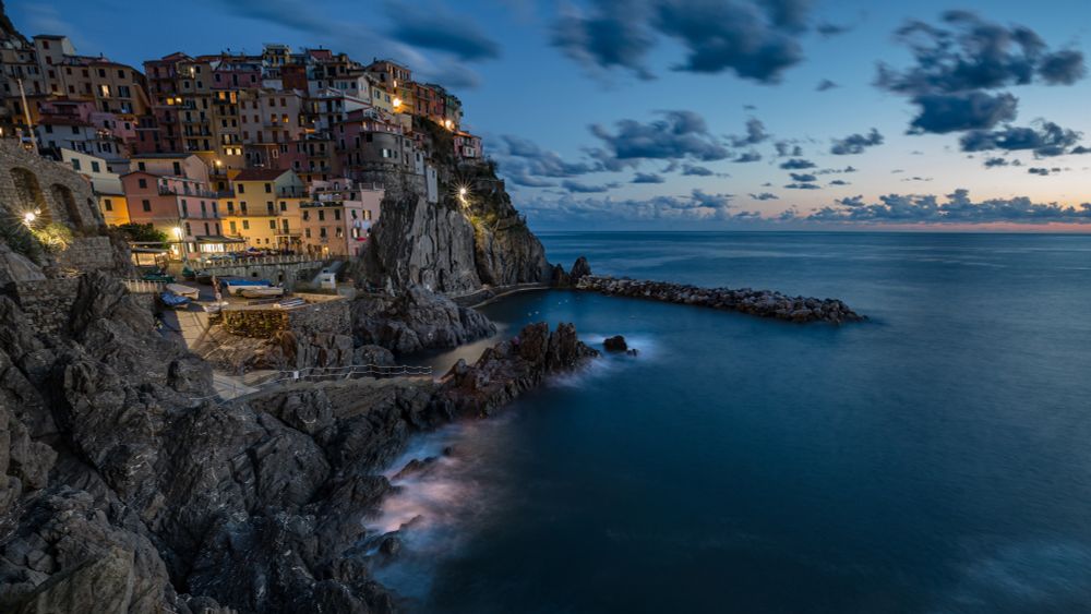 City lights, sea, cliffs, sunset, clouds, blue sky.