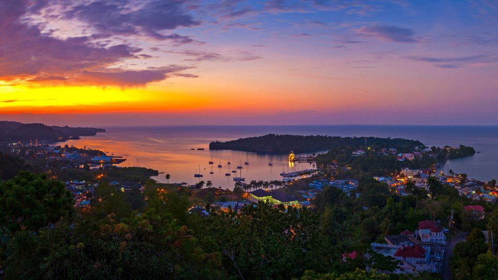 Island, forest, sunset, boats, sea, city lights, sunlight, clouds, blue sky.