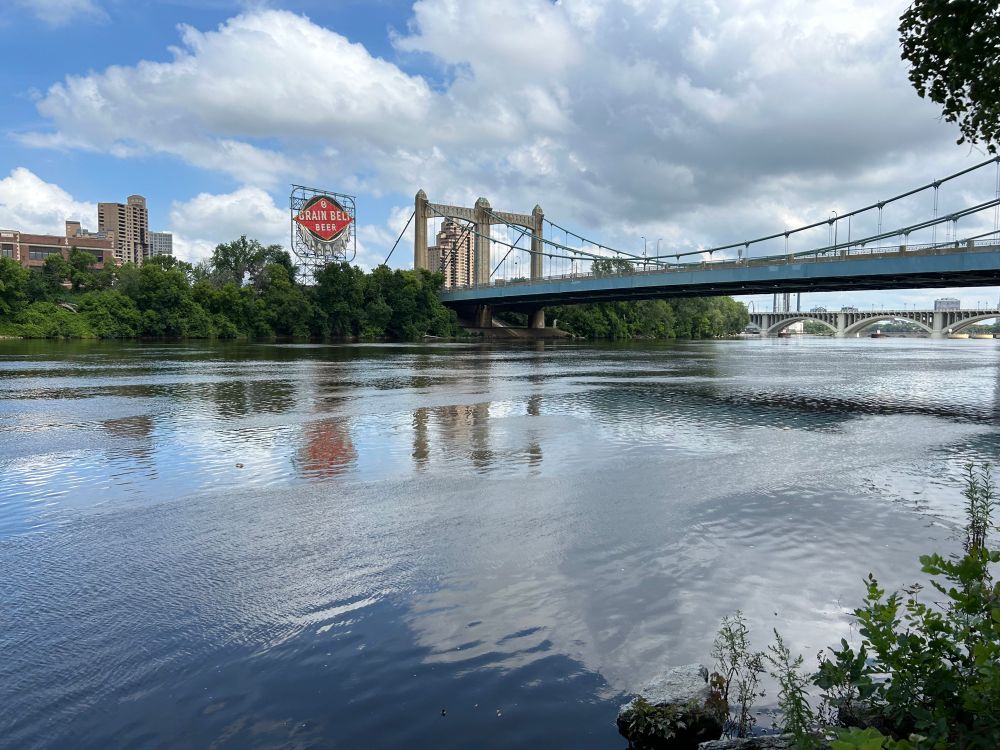 A panoramic view of the Mississippi River, with two bridges visible as well as the Grain Belt Beer sign