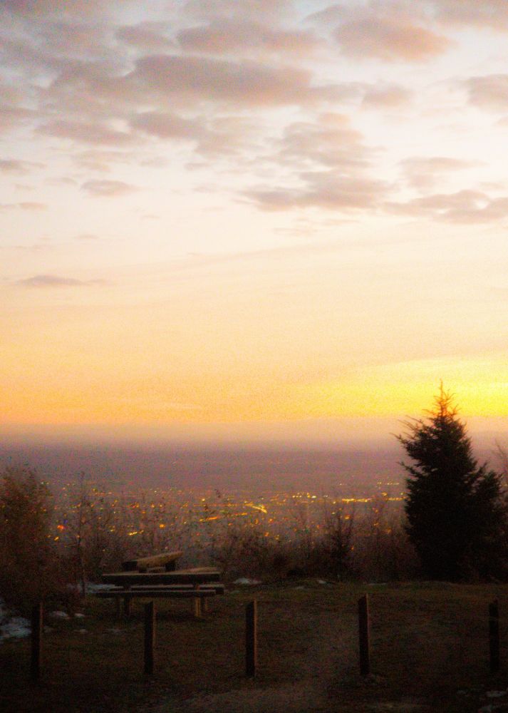 View of a city from a hill during sunset hours. A wooden table in front view.