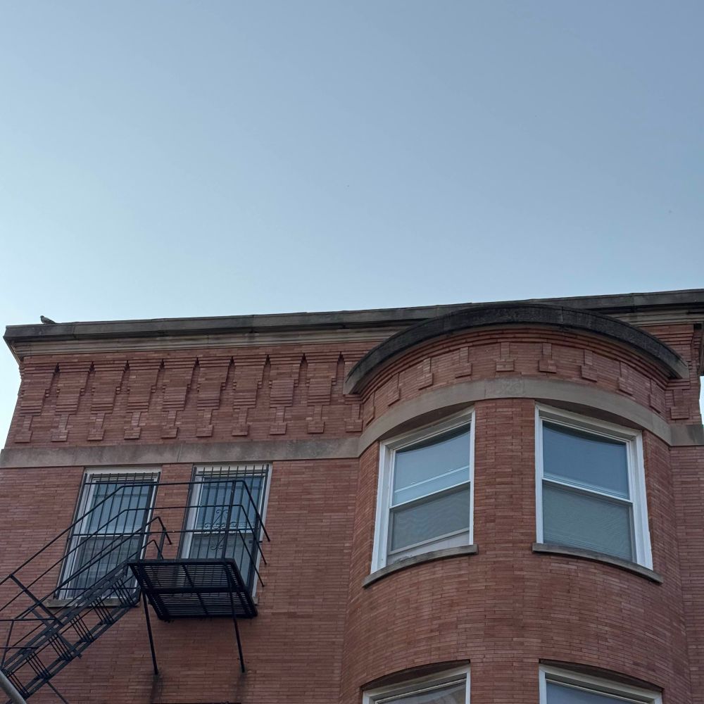 a photo of my first apartment, the third floor of a three flat with the vertical bump out windows on one side and two more windows on the other side that are flat and have a fire escape