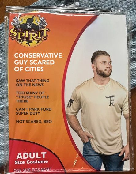 A Halloween costume titled “Conservative Guy Scared of Cities.” The image features a white man with a beard in jeans and a tee shirt stereotypical of those obsessed with military ethos. 