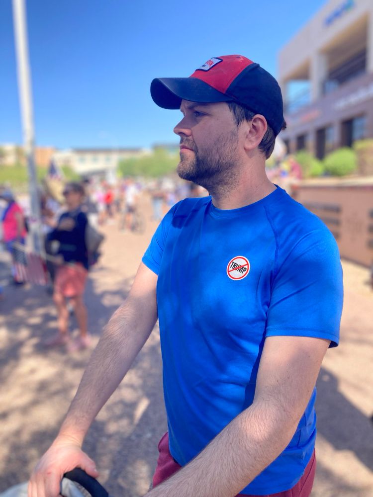 A white guy with a ball cap on and a sticker with the words “TRUMP” crossed out. 
