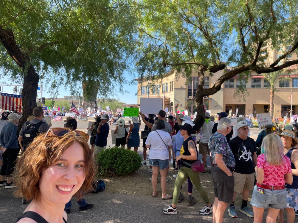 Woman smiling standing in front of a crowd of protesters. 