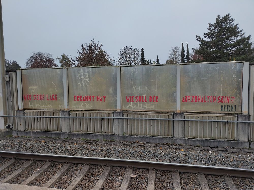 Foto eines Graffiti an einer Bahnhofswand: "Wer seine Lage erkannt hat, wie soll der aufzuhalten sein - Brecht" steht da. 