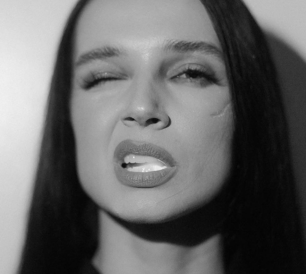 Poppy com um olho fechado e o outro entreaberto, além de um lado de sua boca estar entreaberta