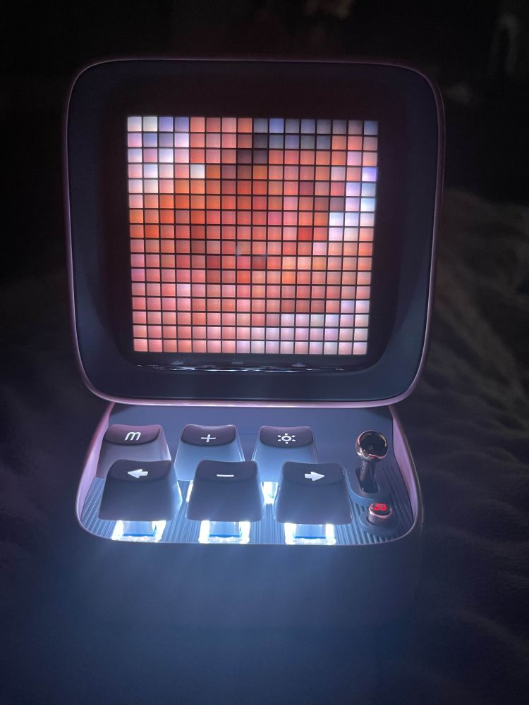 A small, pink computer with a very pixelated image on it. 