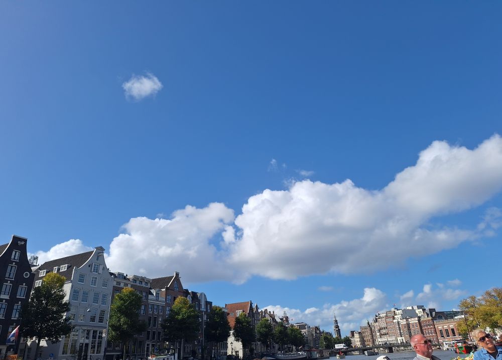 Picture from a boat overlooking a part of Amsterdams beautiful Hauses and a blue skye.