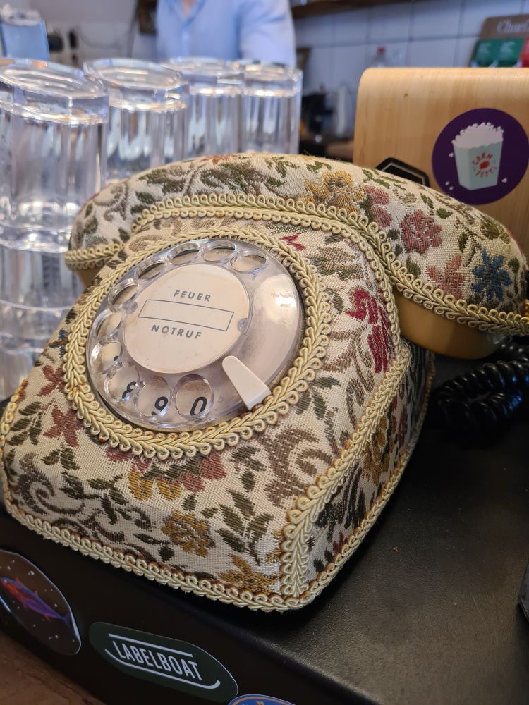 Telefon mit Wählscheibe aus den 70er Jahren in einem Brokatmantel