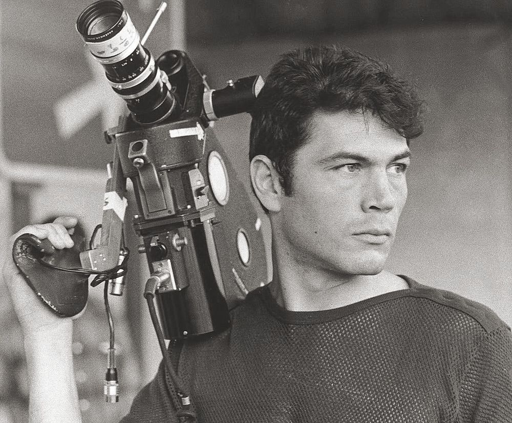 Robert Forster played the leading role of "John Cassellis," a hardened TV news cameraman, in the 1969 film Medium Cool. 

The movie, set against the backdrop of the 1968 Democratic National Convention in Chicago, blends fictional narrative with documentary footage to capture the intense social and political upheaval of the era. 

Initially, Cassellis is portrayed as detached and focused on capturing dramatic footage, even before calling for help at a car crash scene, for example. 

He is portrayed as being "the essence of cool, professional detachment" in his pursuit of audience-grabbing stories. However, his perspective shifts when he learns that his network is cooperating with the FBI by providing them with footage to track down dissidents. 

This discovery awakens a sense of social responsibility in him, leading him to confront the ethics of his profession and the potential for media manipulation. 

Medium Cool explores themes of media ethics, social upheaval, and the impact of the Vietnam War on individuals and society. It is particularly noted for its use of cinéma vérité style and its controversial blend of staged scenes with real-life events, including footage shot amidst the riots surrounding the 1968 Democratic National Convention. 

The film's title itself refers to Marshall McLuhan's concept of television as a "cool" medium.