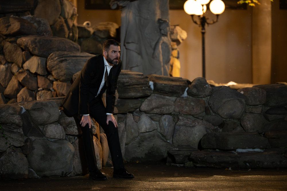 Wolf outside of the gala, leaning/sitting against a atone wall with his hands on his knees. He looks shocked. He still wears his black tuxedo and white shirt but his bow-tie is open.