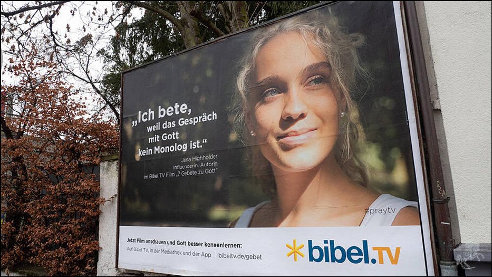 Eine riesengroße Plakatwerbung von oder für bibel.TV. Zu sehen ist das Gesicht von Jana Hochhalter. Zitat: "Ich bete, weil das Gespräch mit Gott kein Monolog ist."