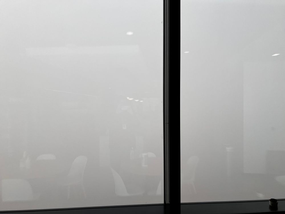 Large office windows, reflecting break room chairs inside. Outside is a thick blanket of fog, obscuring literally everything. (On the right side there’s a vertical line that looks like a building—that’s an interior wall being reflected)