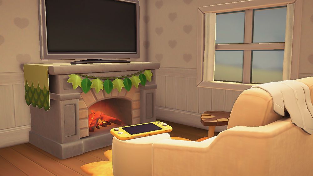another screenshot of my home in animal crossing ! it’s a picture of my living room (still a wip) there’s a messy couch with a yellow switch lite laying on the ottoman, a leaf-shaped side table, and a tv above a warm fireplace (so cozy) ♡