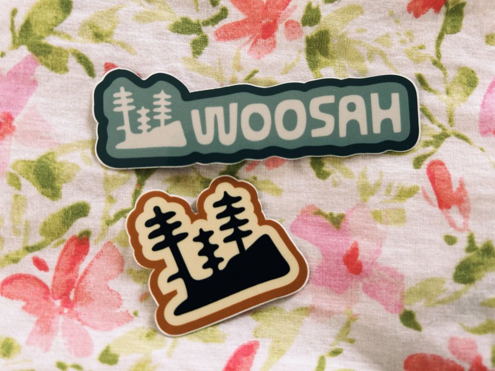 2 stickers on floral bedding: one is off the artists logo “woosah” with the little trees, and another is of 3 little trees on rocks