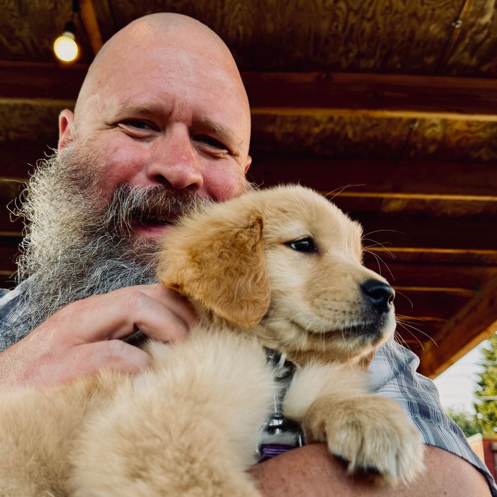 Bearish man with fluffy, golden retriever puppy