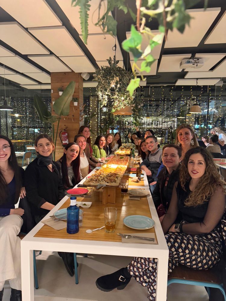 Foto en la mesa, con algunas mentoras y mentorizadas y una pizza de dos metros