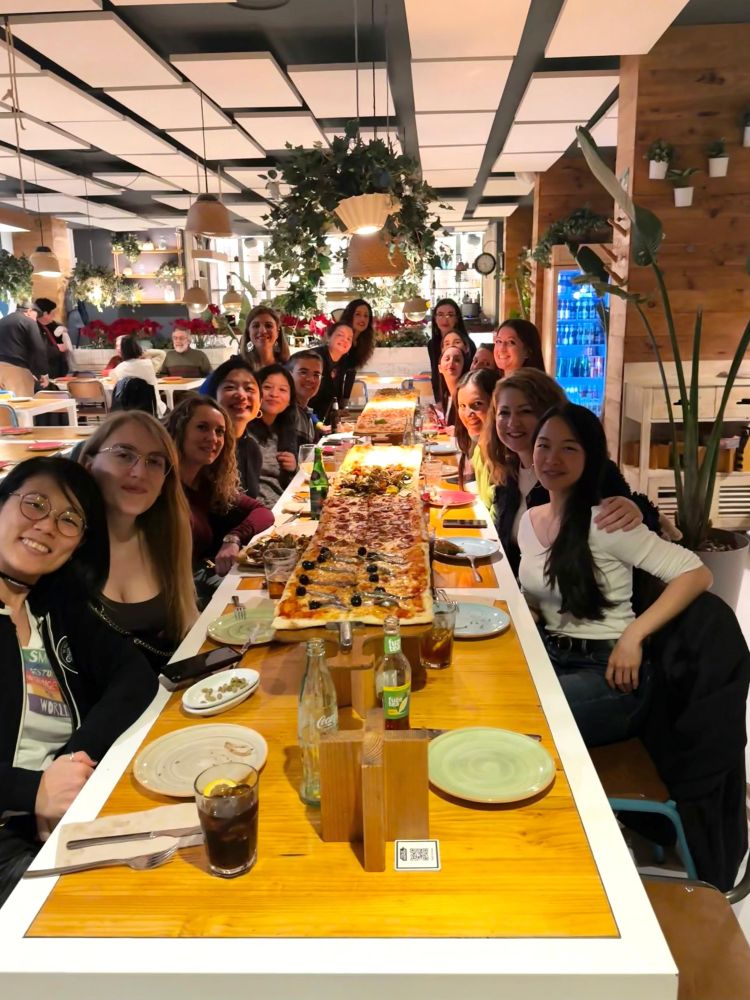 Foto en la mesa, con algunas mentoras y mentorizadas y una pizza de dos metros