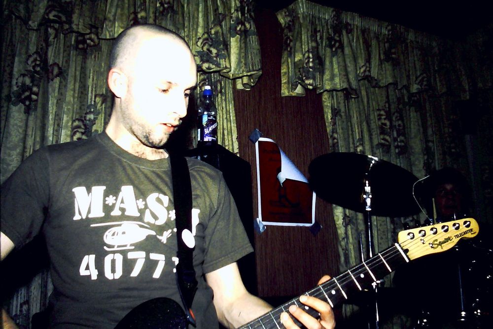 Dre Langlois on guitar in a M.A.S.H t-shirt and a past life